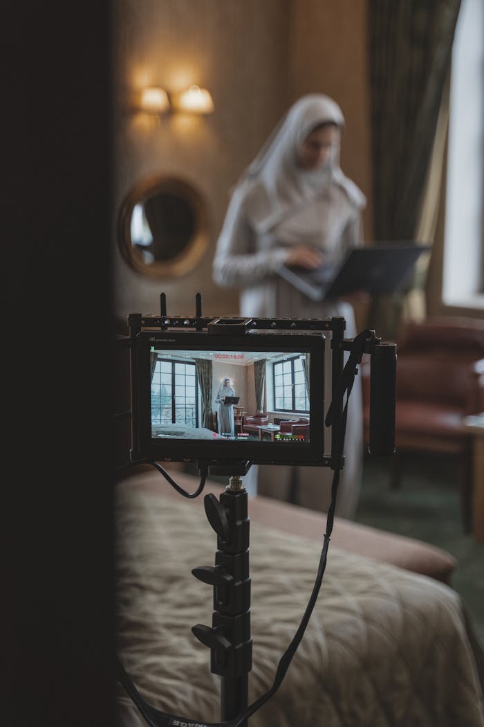 about-us-01 Muslim woman in hijab setting up camera indoors for content creation, showcasing creativity and technology.